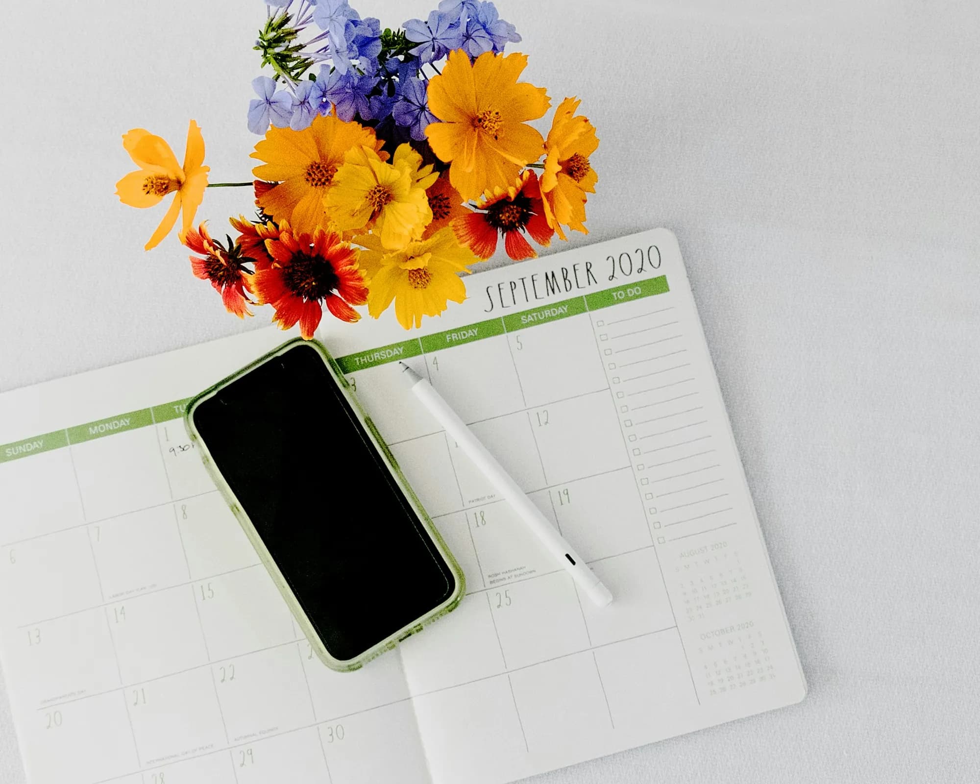 A calendar and smartphone on a desk in morning light