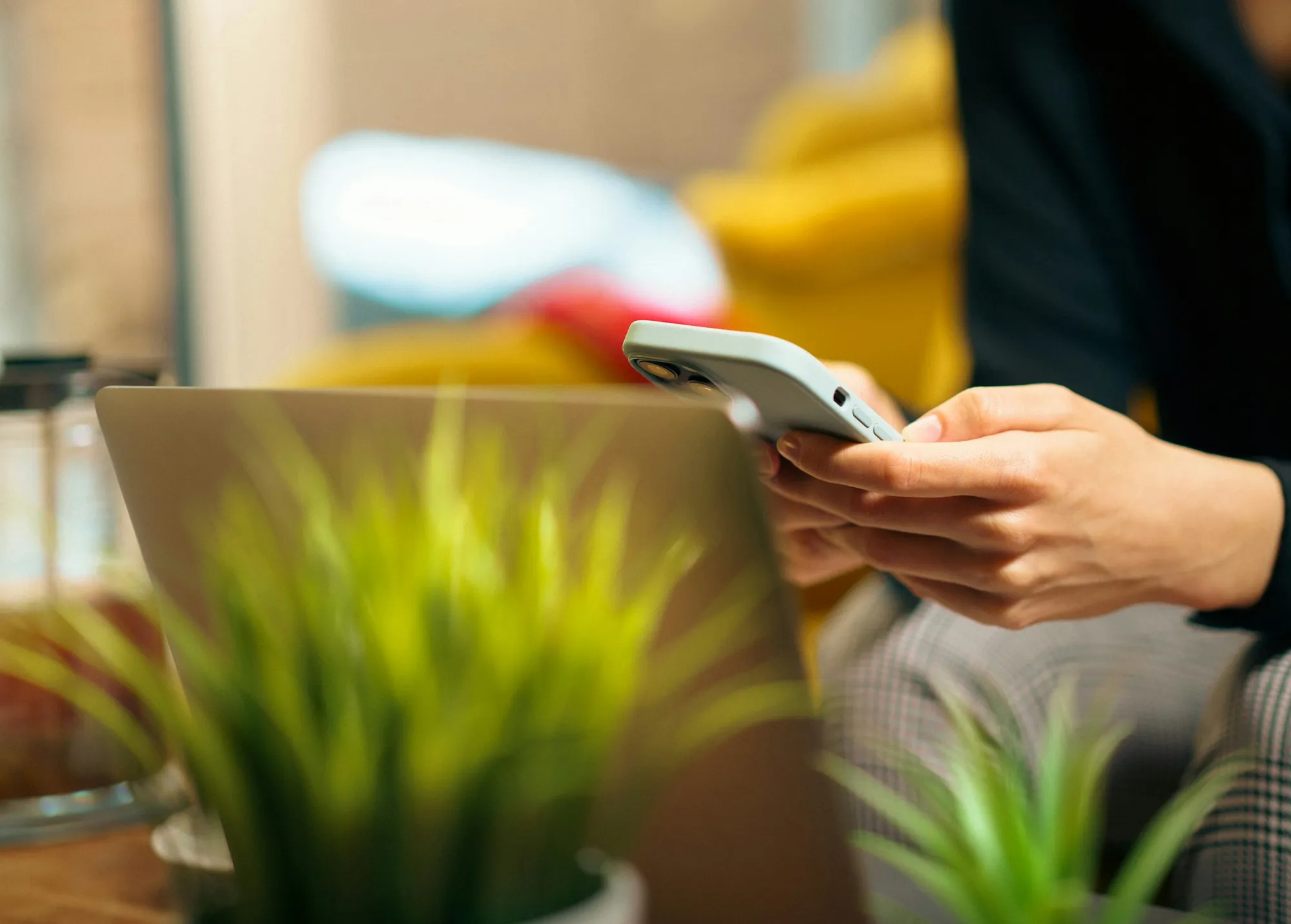 A phone held while sitting on a sofa in a bright living room