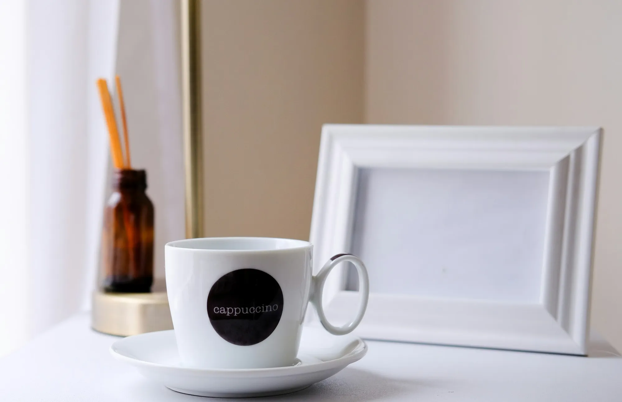A smartphone beside a coffee cup on a bedside table