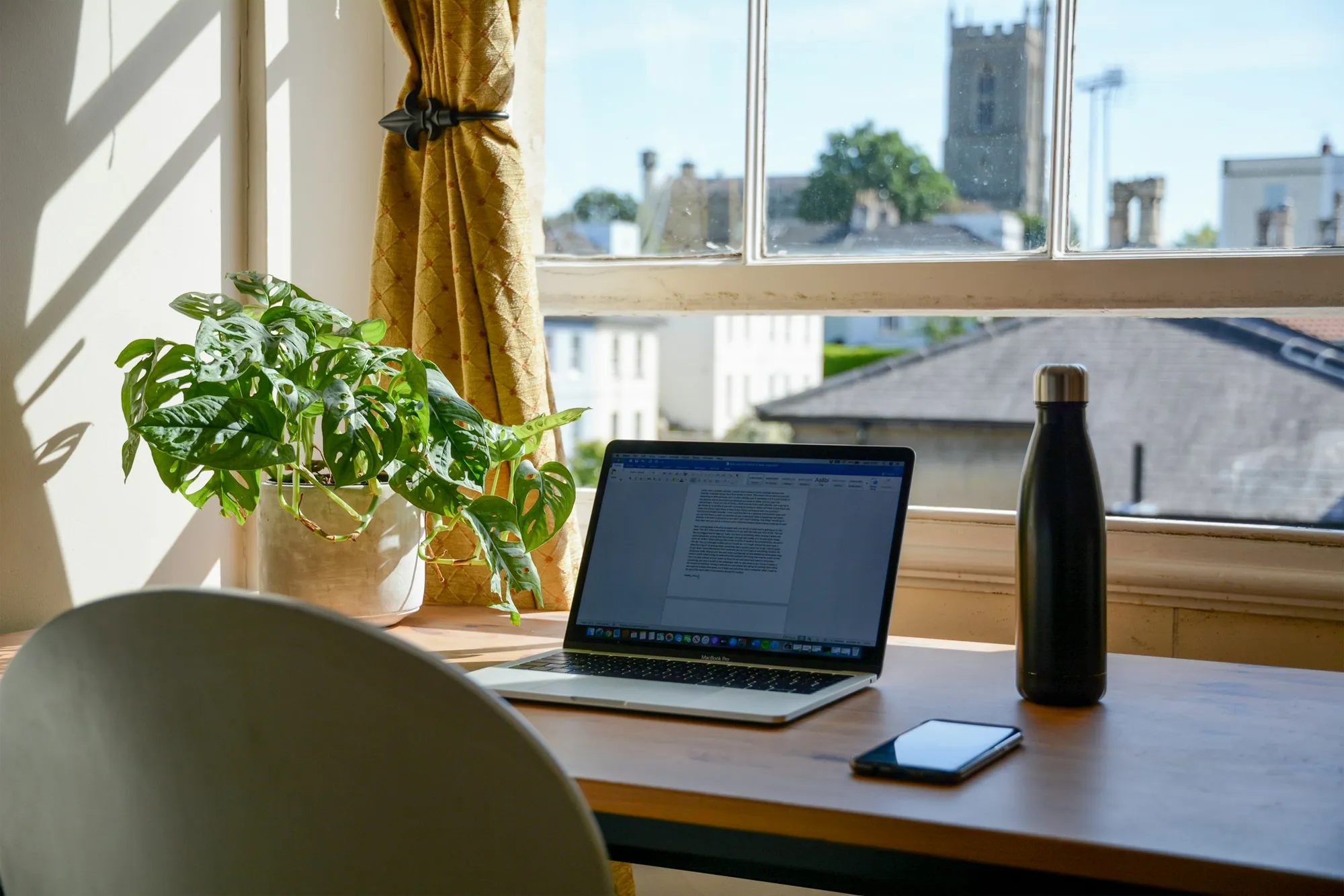 A laptop and notebook on a bright home office desk