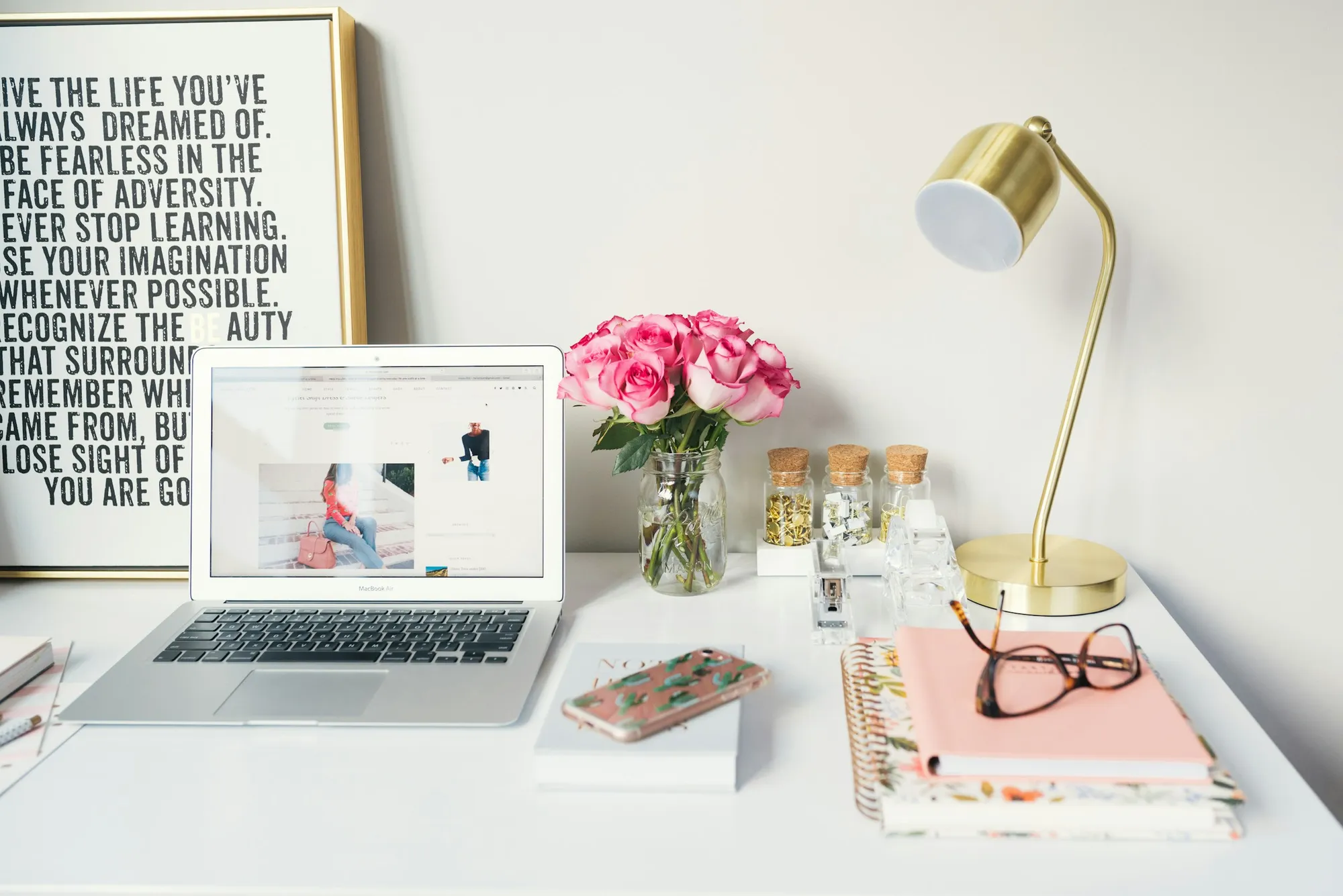 Books, a laptop and notebook arranged on a desk