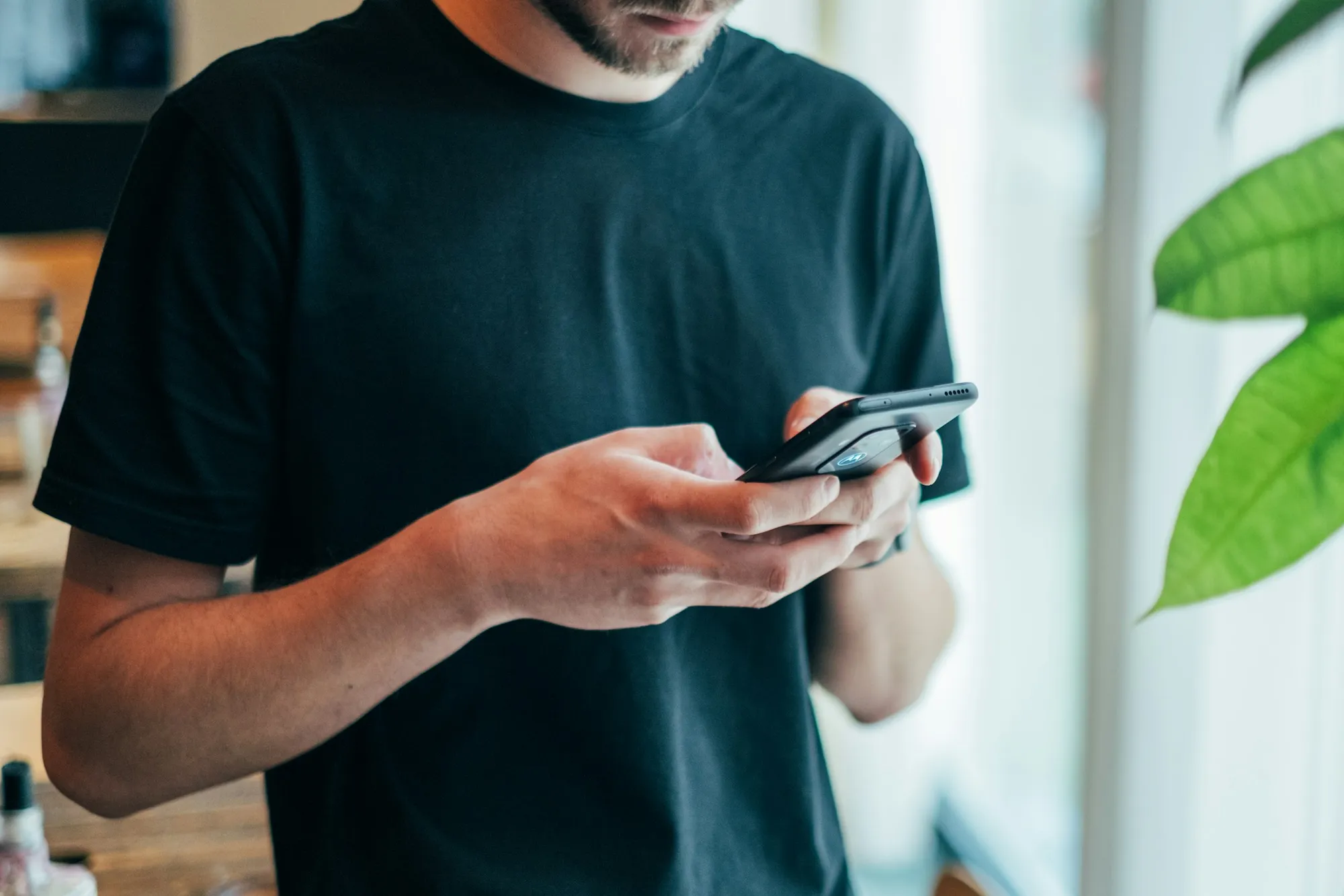 Someone typing a message on a phone in a warmly lit room