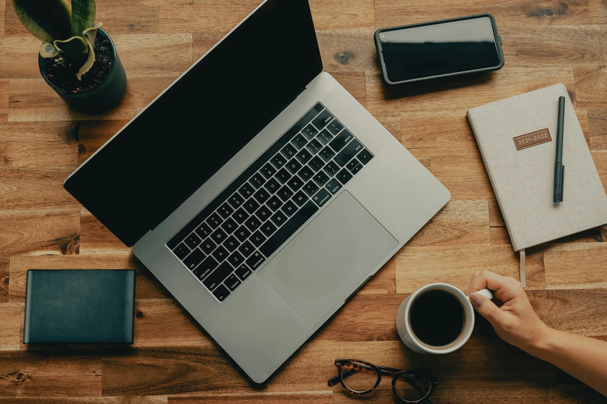 Coffee, a notebook and a laptop on a planning desk