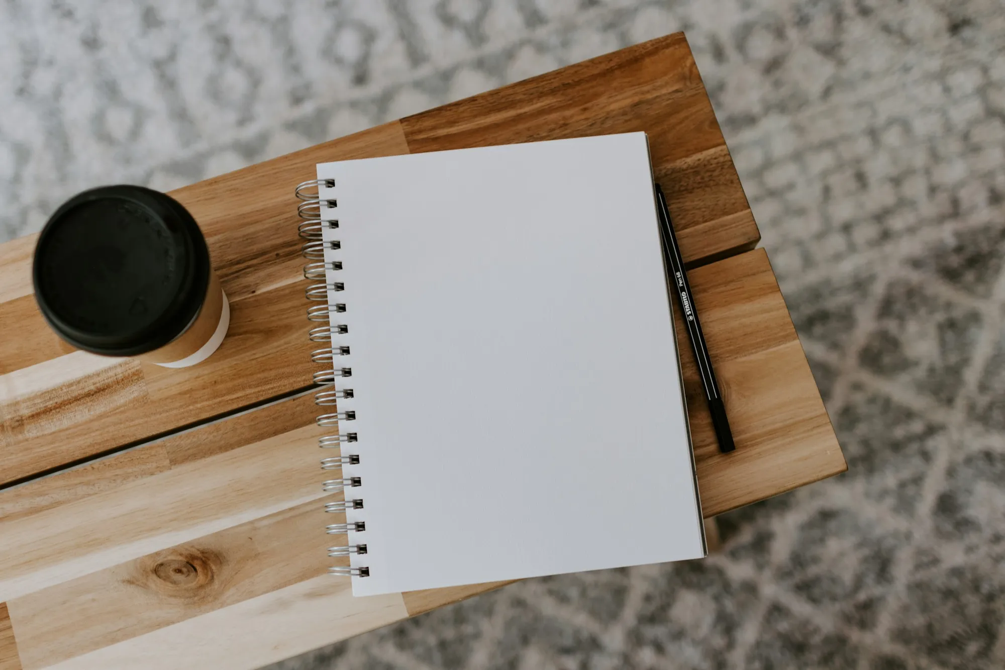 A stack of books and a notebook on a desk