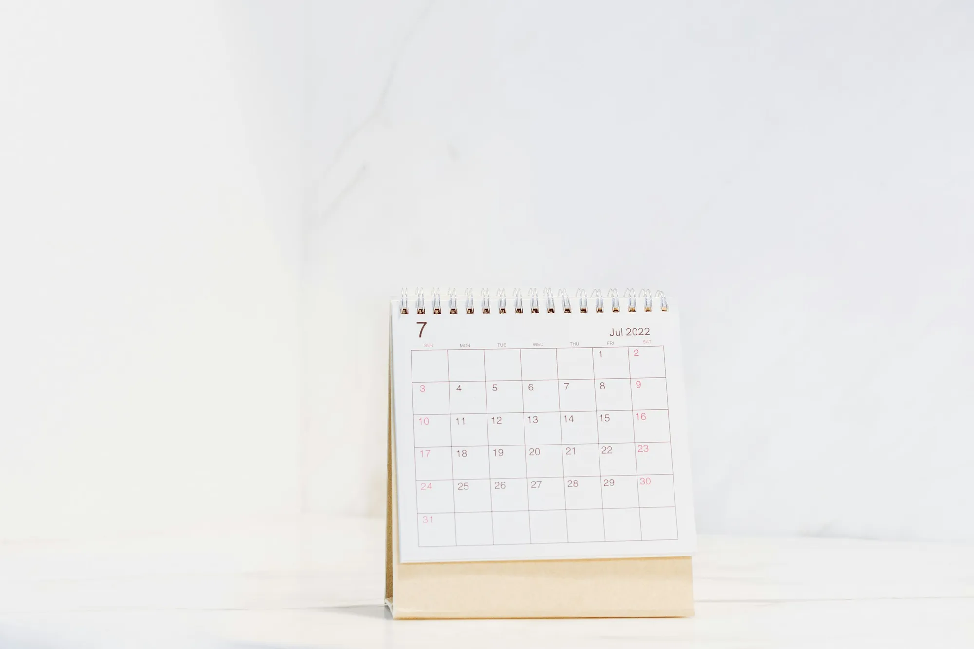 A wall calendar above a desk with a laptop