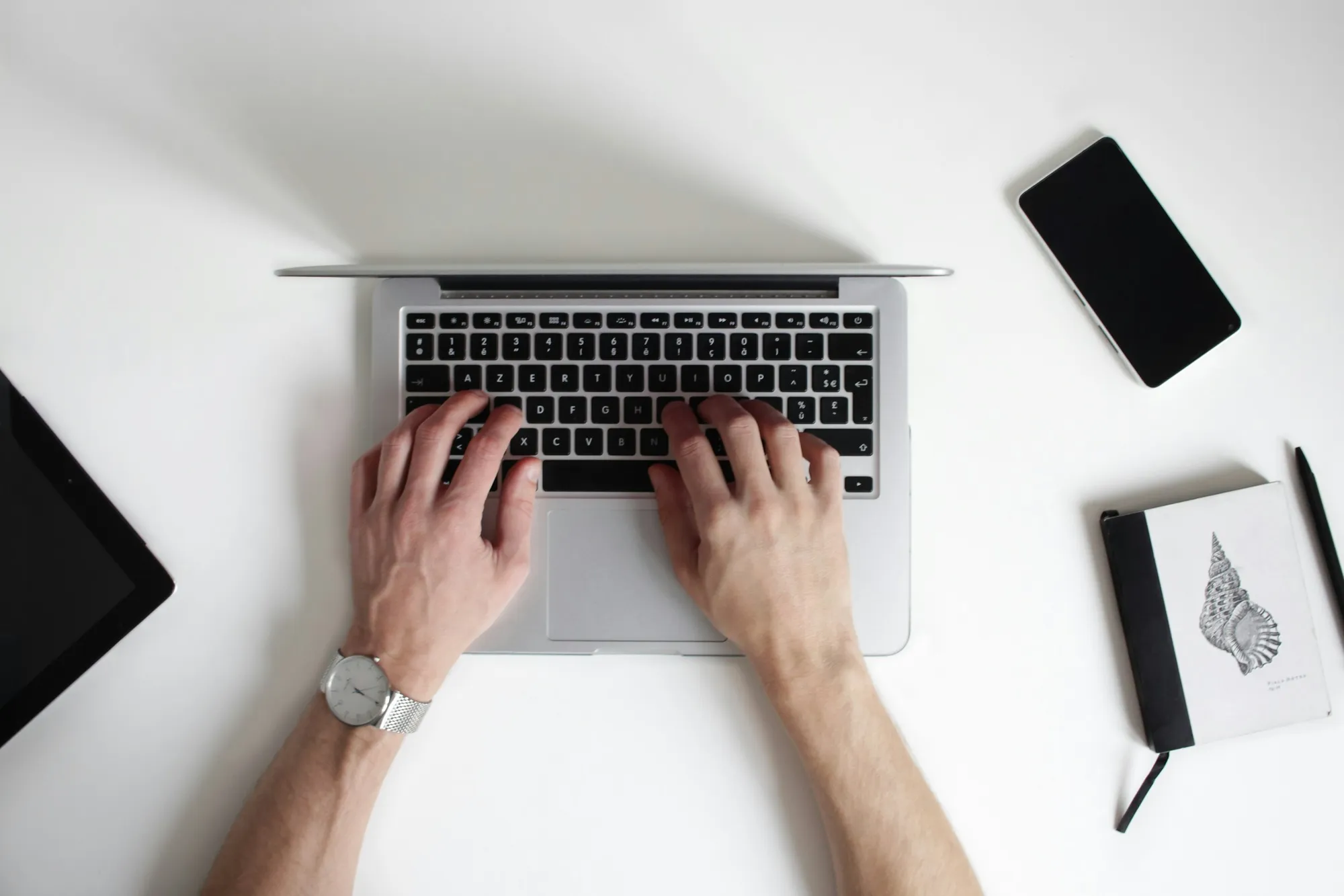 A laptop, tablet and notebook on a desk