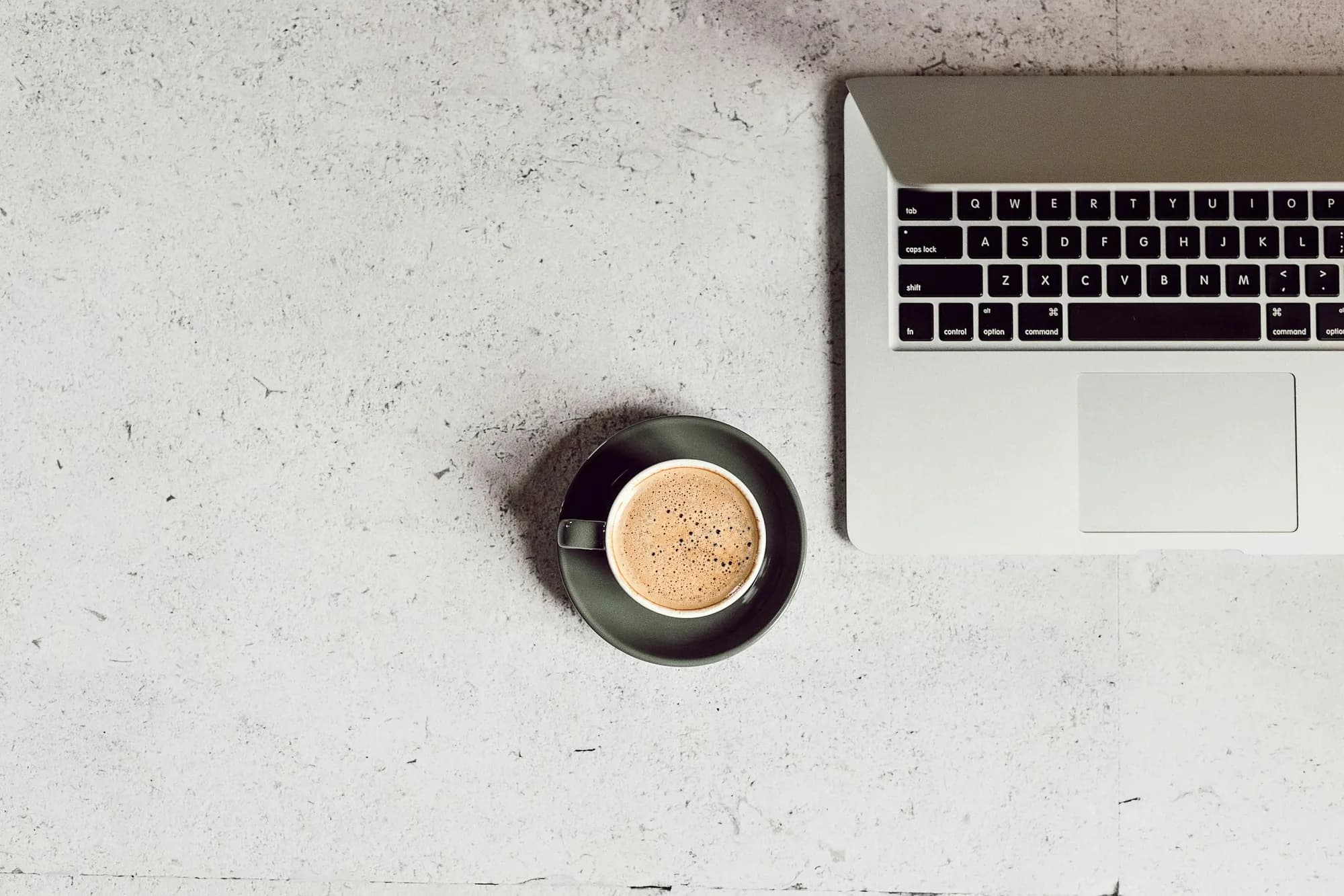 Coffee, a notebook and a laptop on a planning desk